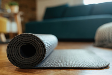 Close-up of rolled exercise mat on parquet floor.