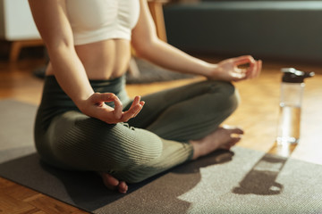 Close-up of athletic woman practicing Yoga in lotus position.