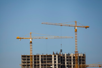 Construction site with cranes against the blue sky