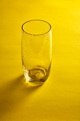 Transparent empty glass in yellow background