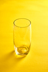 Transparent empty glass in yellow background