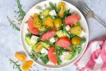 Avocado salad with grapefruits, tomato, feta cheese, arugula and sunflower seeds. Top view with copy space. Healthy eating.