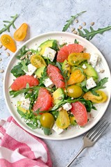 Avocado salad with grapefruits, tomato, feta cheese, arugula and sunflower seeds. Top view with copy space. Healthy eating.
