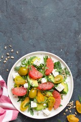 Avocado salad with grapefruits, tomato, feta cheese, arugula and sunflower seeds. Top view with copy space. Healthy eating.