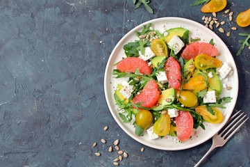 Avocado salad with grapefruits, tomato, feta cheese, arugula and sunflower seeds. Top view with copy space.