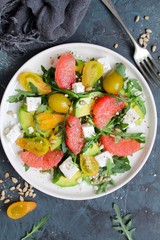 Avocado salad with grapefruits, tomato, feta cheese, arugula and sunflower seeds. Top view with copy space. Healthy eating.