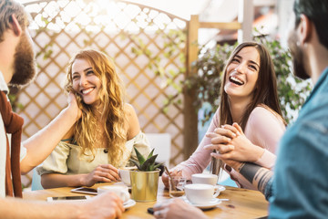 Happy friends drinking cappuccino in cafeteria bar - Young romantic couple having fun sharing time together -  Love relationship and social gathering people lifestyle concept