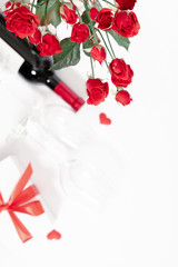 Red roses, flowers bouquet, gift, wine and glasses for wine on white background. Women's Day, Valentine's Day, Birthday. Flat lay, top view, copy space