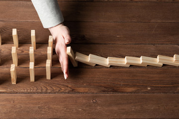 Businesswoman protecting dominoes from falling