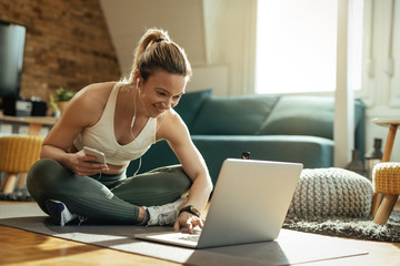 Smiling athletic woman surfing the net on laptop at home.