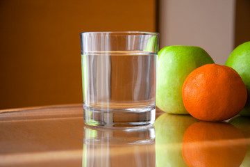 glass with clean water on the table and fruits