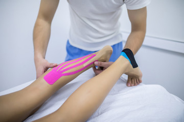 Obraz na płótnie Canvas Manual, physio and kinesio therapy techniques performed by a male physiotherapist on a training plastic spine and a female patient leg