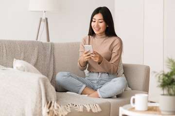 Weekend at home. Girl relaxing on sofa with smartphone