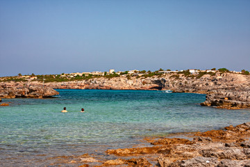 Some tourists bathe in the clear and blue waters of a bay in Formentera in the Balearic islands of...