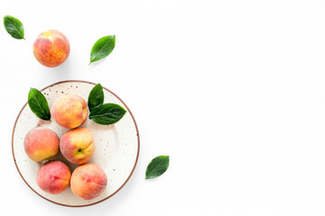 Summer fruits. Ripe red peaches on plate on white table top-down copy space