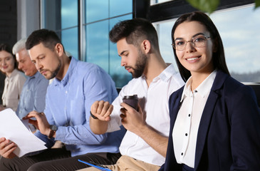 Young woman with eyeglasses waiting for job interview in office hall