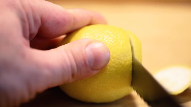 male hand cutting lemon in slices