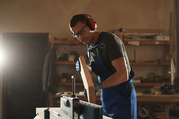 Professional carpenter working with wood in shop
