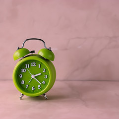 Bright green alarm clock on a light background.