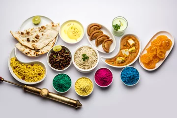 Papier Peint photo autocollant Manger Happy Holy concept  showing Indian assorted lunch food like chicken, paneer butter masala, naan, jeera rice, black chana fry, jalebi, fujiyama, thandai and Farsan with holi colours and pichkari 