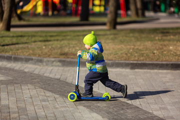 Cute little boy riding a kick scooter