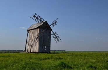 Plakat old wooden four-bladed windmill with clouds in a field at summer