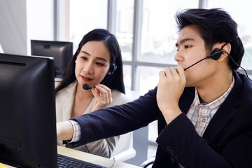 Two Asian call center operator agents working together and help each other. Concept for business,...