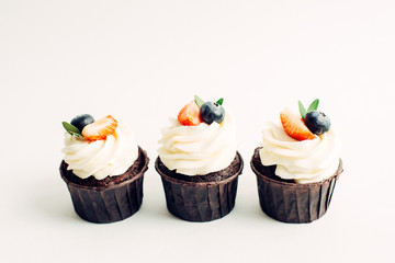 Tasty cupcakes with berries, isolated on white