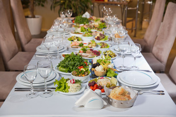 Set of a dish with spoon, fork and knife on white table.Table setting on white table . Served holiday table, cutlery, crockery, glasses, plate, fork. Salads and gums .