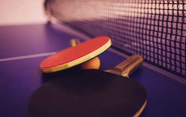 Two table tennis or ping pong rackets and balls on a blue table with net