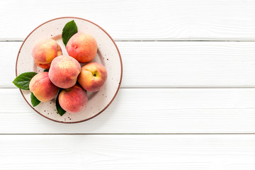 Summer fruits. Ripe red peaches on plate on white wooden table top-down copy space