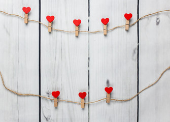 Heart shaped clips hanging on the rope with wooden background.