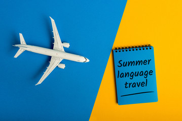 Summer language travel - message on color background with airplane toy. Learning English language and studying abroad
