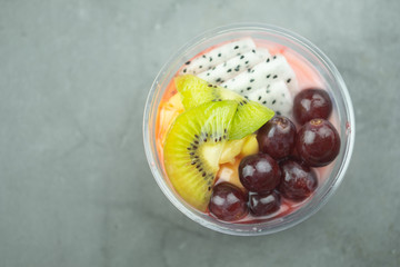 Plastic bowl yogurt smoothie with fresh fruits, Kiwi, grape and dragon fruit slice.
