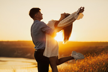 Couple romantic in love at beach sunset. Happy young couple embracing enjoying sunset during travel holidays vacation. 