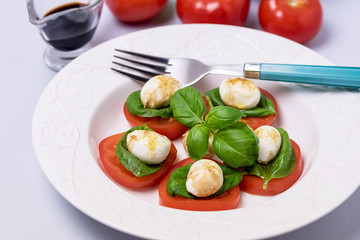White Plate of Classic Italian Caprese Salad Ripe Tomatoes Fresh Basil Leaf Salad and Ingredients Horizontal