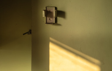 A dusty remote control bracket and holder for an air conditioner mounted on a green wall.