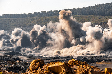 Explosive works on open pit coal mine industry with dust and puffs of smoke
