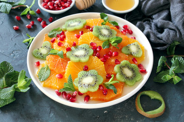 Fruits salad: kiwi, orange, pomegranate and mint served with honey. Healthy eating. Top view with copy space.