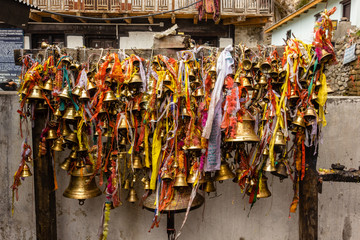 Bronze temple bells with prayers written on colorful ribbons inside the ancient Hindu temple at...
