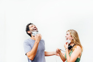 Young couple in the street smiling and taking off their mask