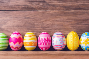 Fototapeta na wymiar Painted colorful easter eggs on brown wood background