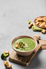 Cream broccoli soup with croutons in a plate on a wooden Board on a light gray background. Concept of healthy nutrition.