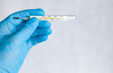 Obraz premium medical mercury thermometer in hand, means of protection from the cold and flu season