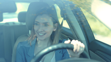 Obraz premium Portrait of beautiful young woman driving car smile look around through big sunny face automobile road travel attractive emotional enjoyment freedom holiday moving outdoors slow motion