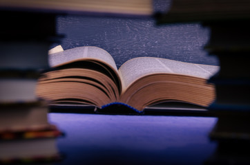 Big book on the table through a stack of books with a place for text, writer day, poet.