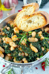 Stewed beans with black cabbage served with toasted bread. Vegetarian and vegan food. Top view with copy space.
