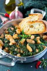 Stewed beans with black cabbage served with toasted bread. Vegetarian and vegan food. Top view with copy space.