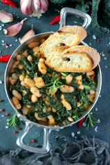 Stewed beans with black cabbage served with toasted bread. Vegetarian and vegan food. Top view with copy space.