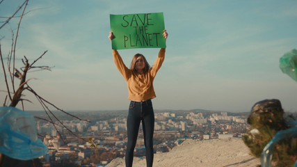 Young woman activist holding encouraging green poster Save the Planet standing calls out slogans...